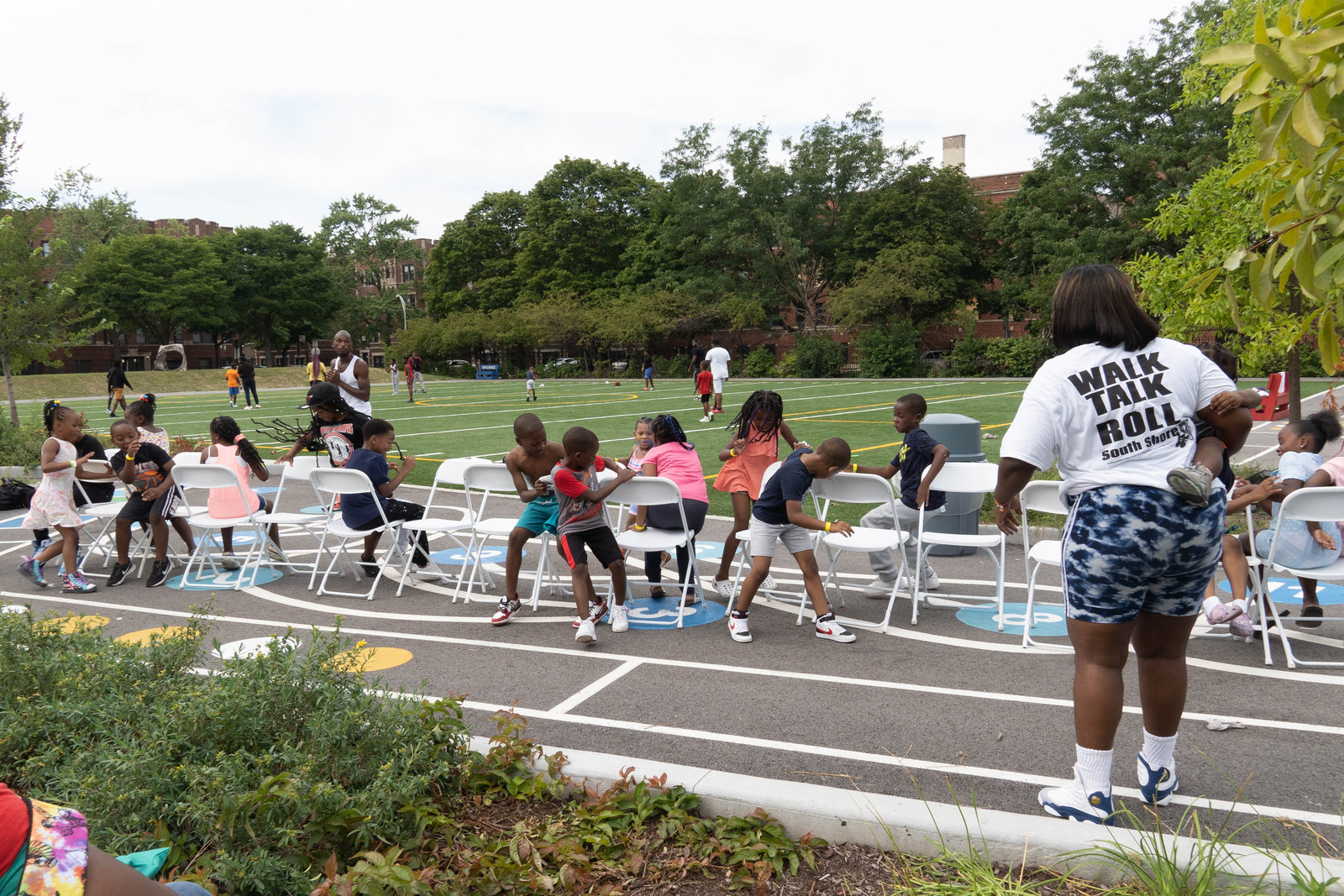 Neighbors gathered in chairs on an outdoor court during a community block party
