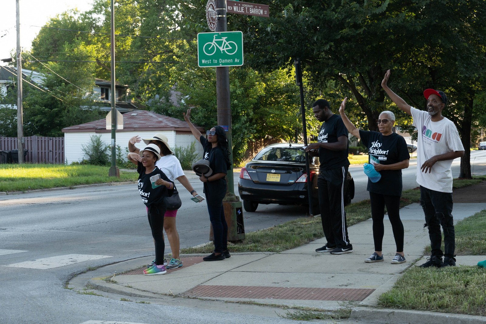 Residents of different generations waving together during a neighborhood walk