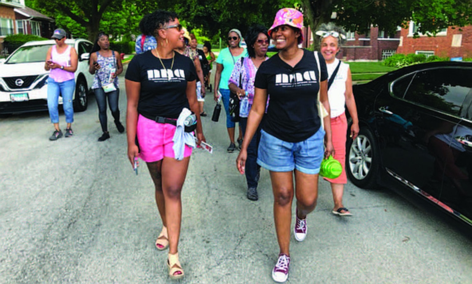 Smiling South Shore neighbors walking together, with two participants in NNA shirts talking at the front of the group