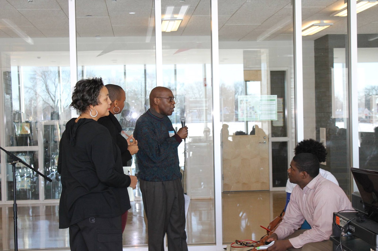A resident speaking into a microphone beside other community members at a town hall